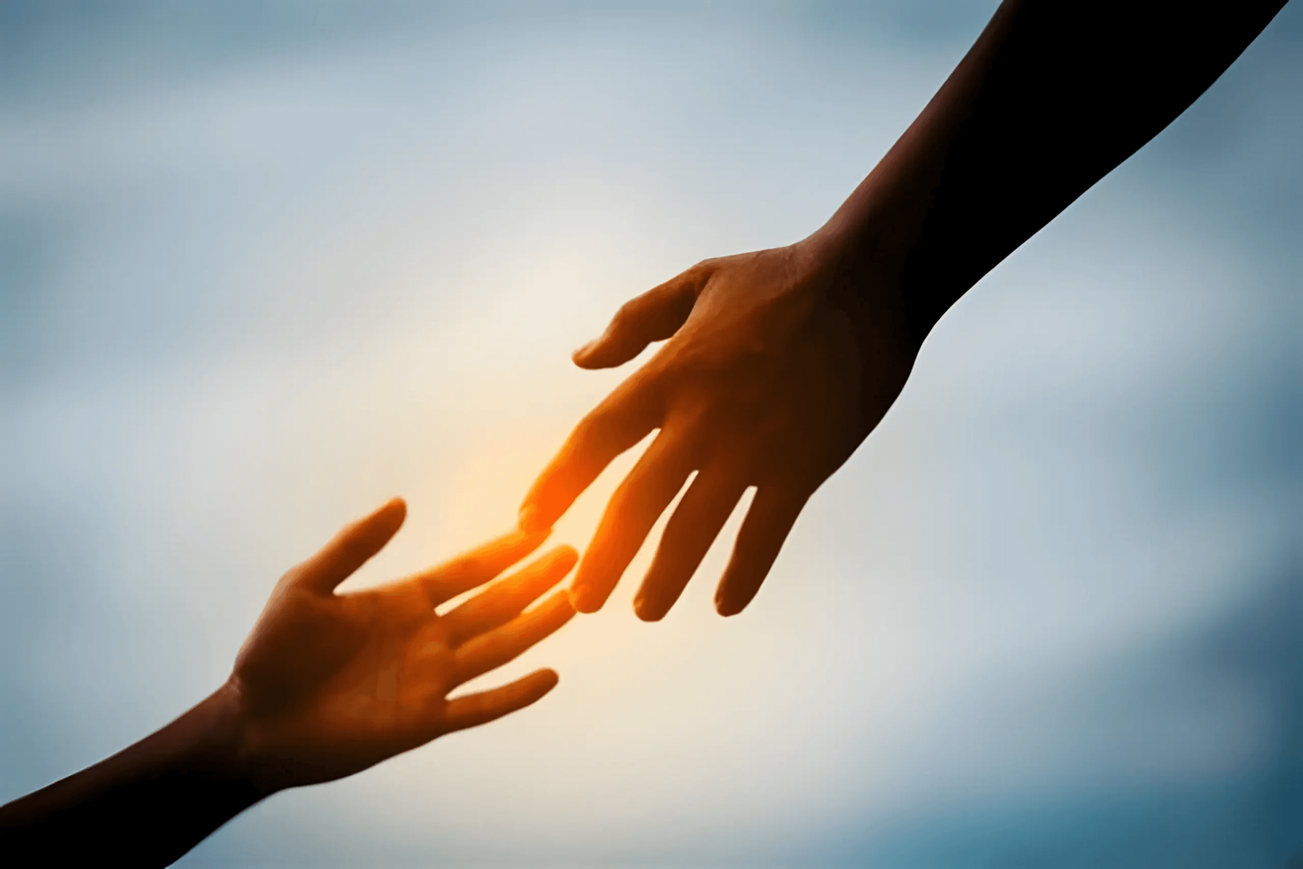 Hands reaching toward each other in warm sunlight