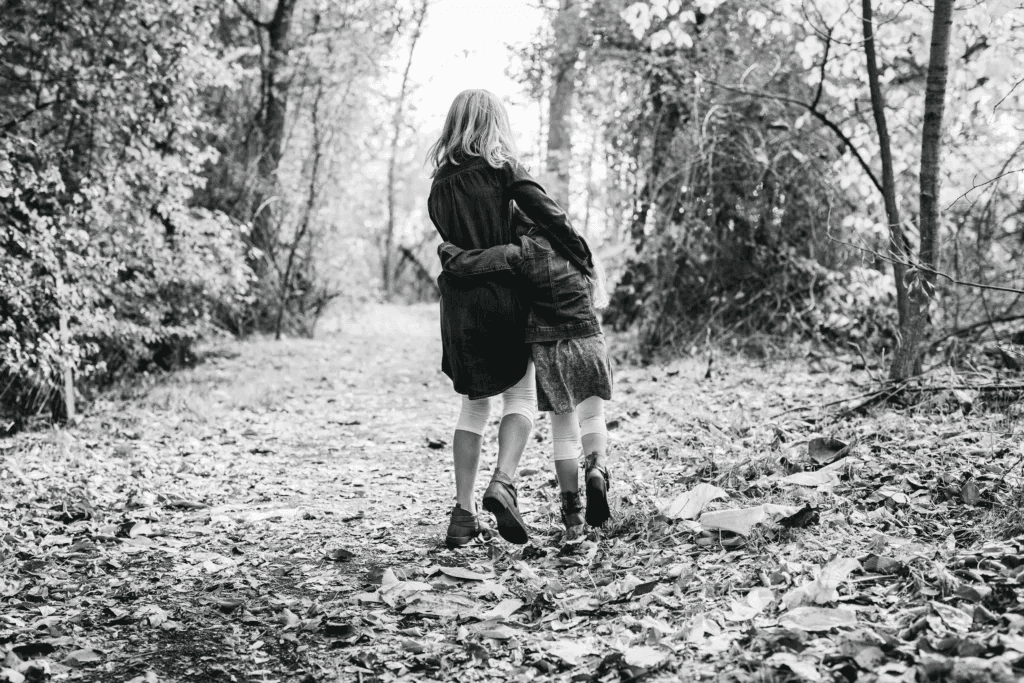 Two siblings embracing on a woodland path